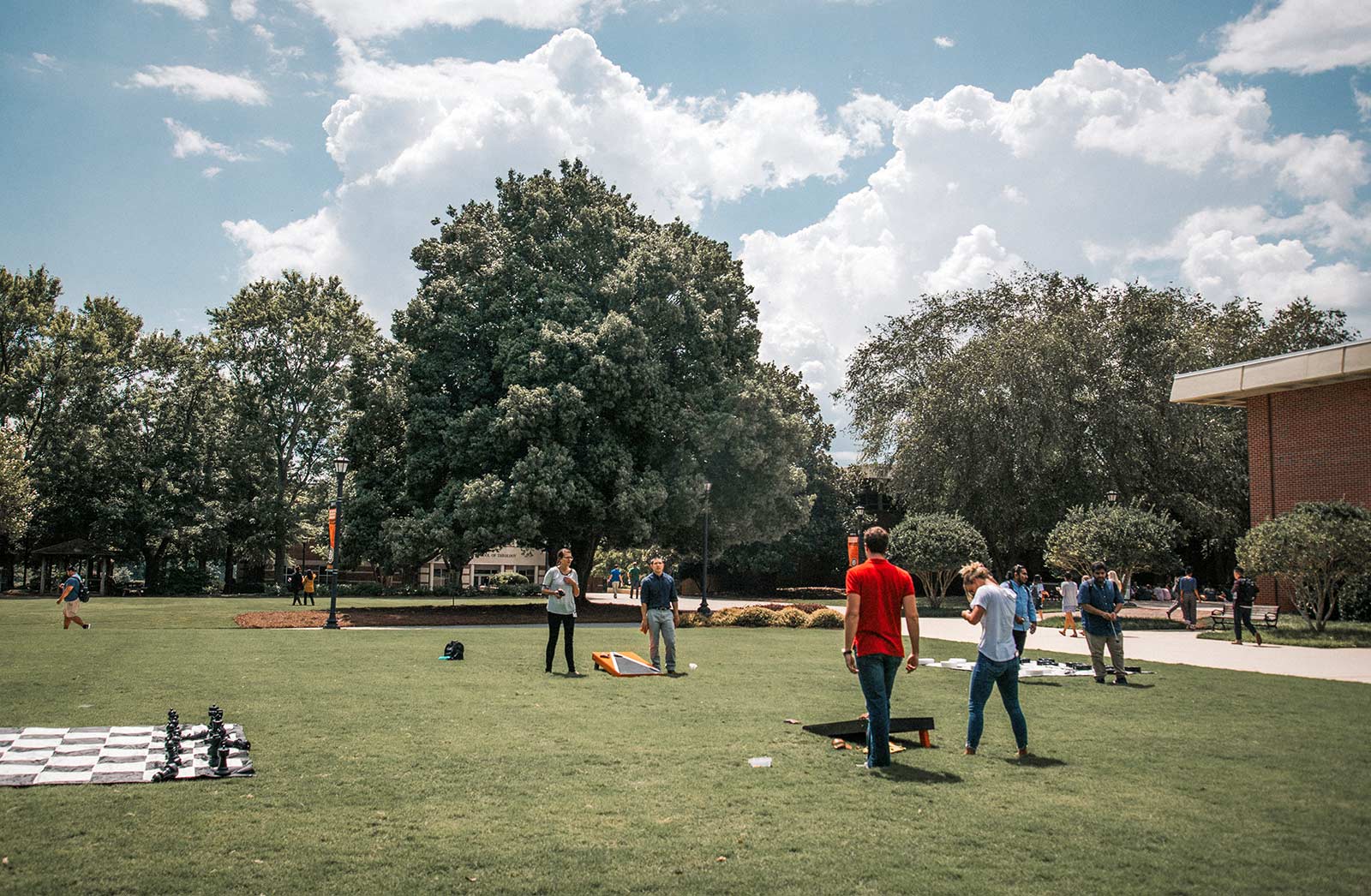 A group of students on the grass playing lawn games like chess and cornhole