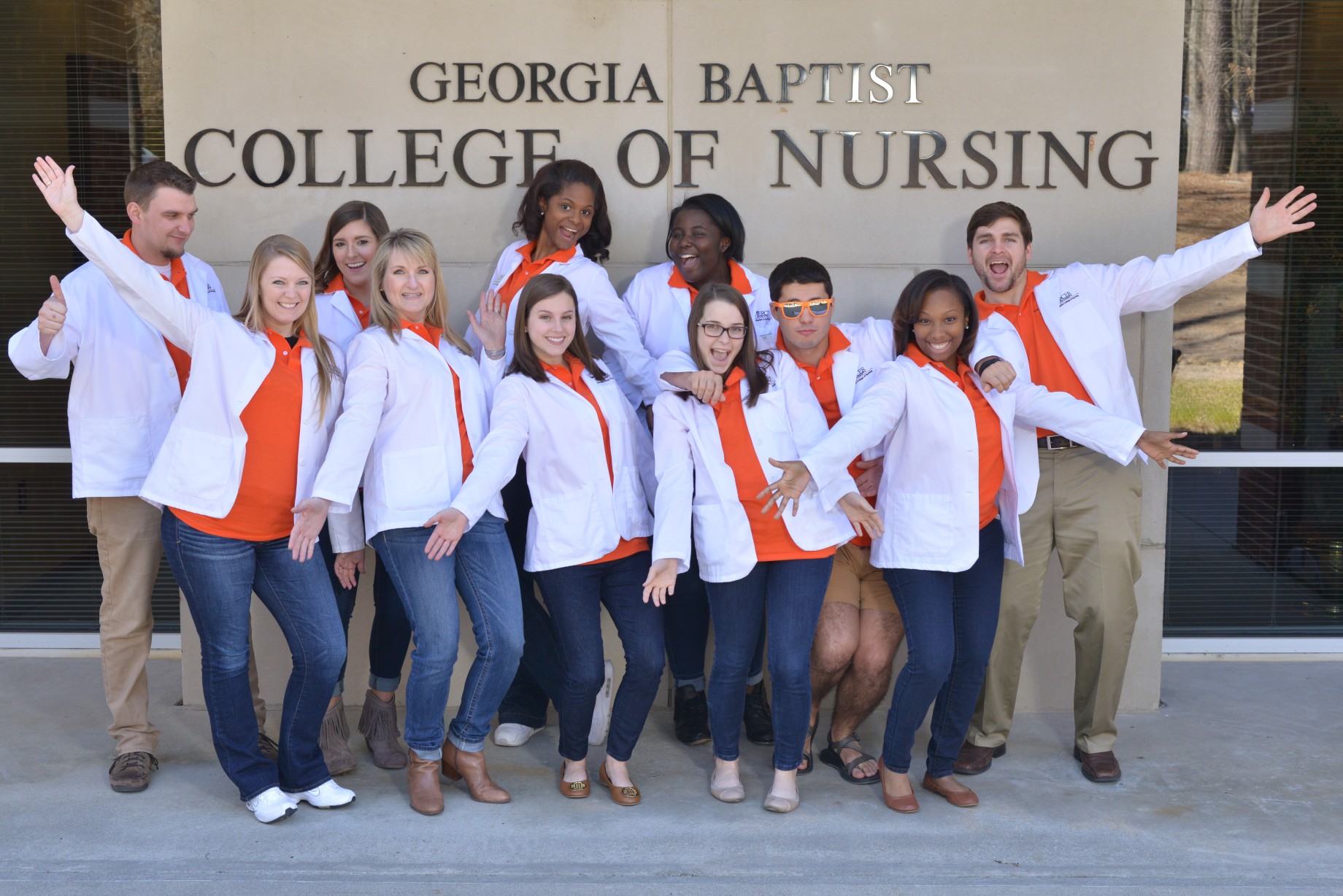 present day photo of students in white coats in front of school of nursing sign