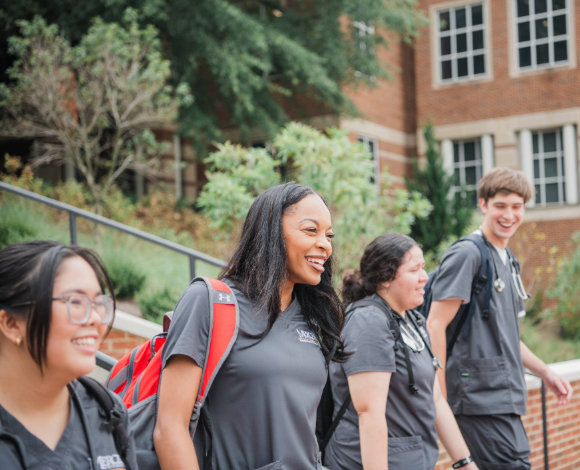 Four nursing students walking down stairs and smiling