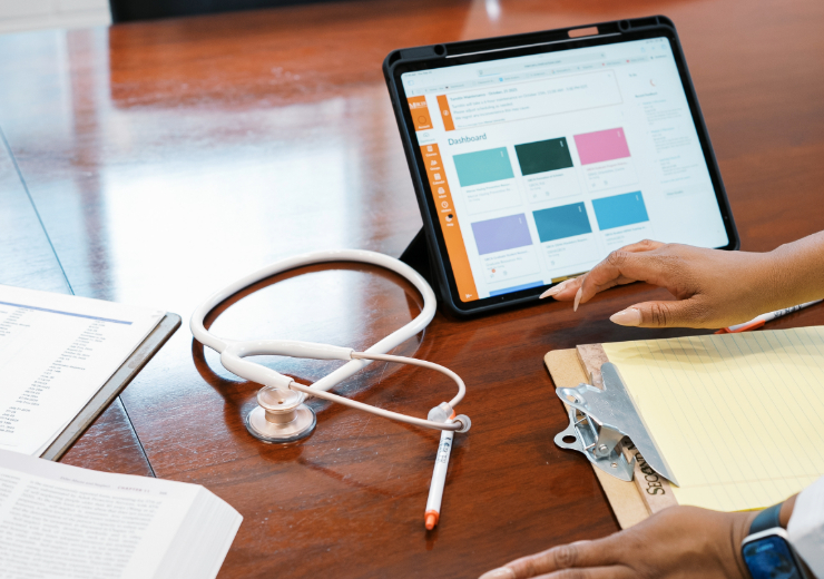 tablet, notebook, stethoscope, and textbook on a table