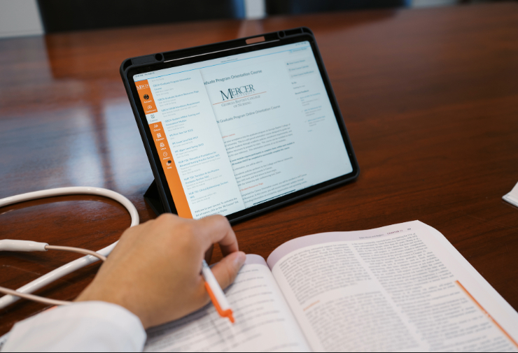 tablet, textbook, and stethoscope on a table