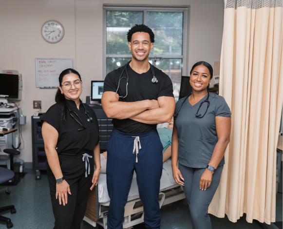three nursing students standing in front of hospital bed