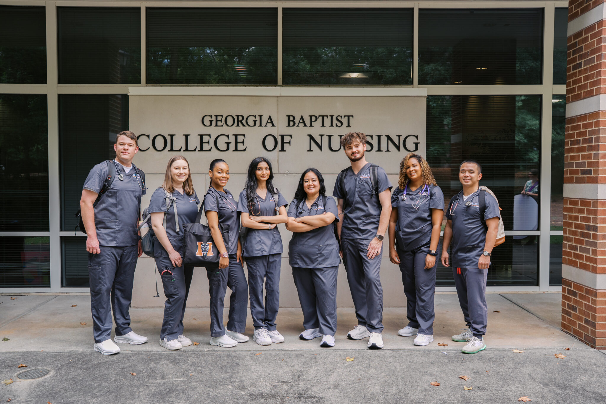 group of nursing students in scrubs in front of the nursing building